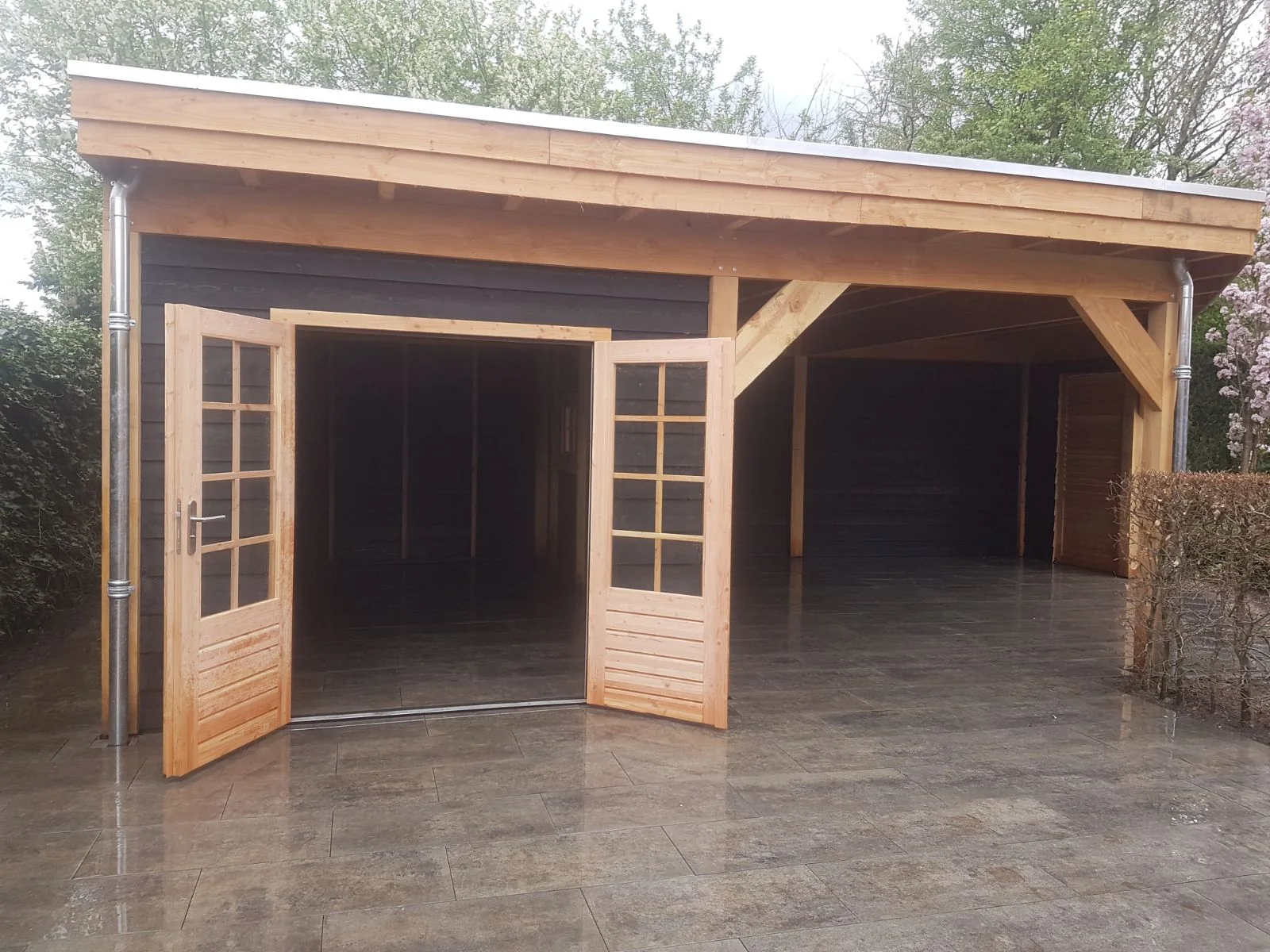 Hetzelfde tuinhuis met de openslaande deuren open, zicht op de overkapping ernaast